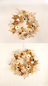 Detail of autumn wreath with maple leaves and pumpkins hanging on a white door