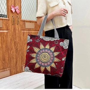 Close-up of ethnic sun flower pattern on red canvas tote with striped handle