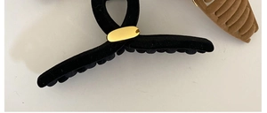 Détails de la texture velours et boucle dorée sur les pinces à cheveux noires et brunes