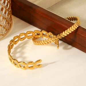 Detail of 18k gold plated stainless steel open bangles with leaf and heart patterns