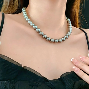 Detailed close-up of a minimalist grey pearl necklace worn by a model on the collarbone