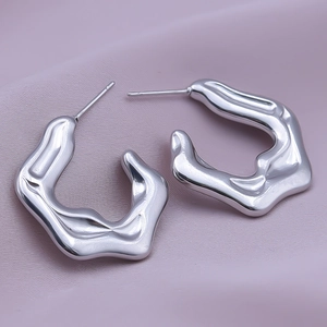 Macro shot of silver irregular molten texture 304 stainless steel earrings on pink silk cloth