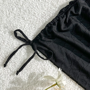 Detailaufnahme von schwarzem Faltenstoff mit verstellbarem Kordelzug und weicher Textur