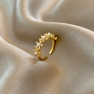 Close-up of gold butterfly ring with micro-set zircon and pearls on silk background