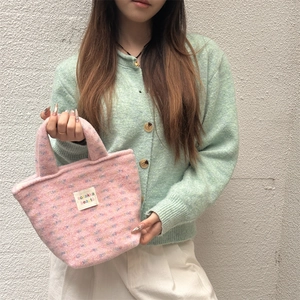 Detailed texture of pink plush tote bag with sozakka beauté woven label on soft fabric