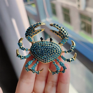 Detailed close-up of a crab brooch with sparkling blue rhinestones and gold metal base