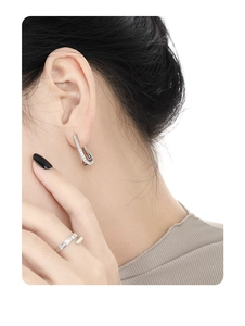 Detail of elegant S925 sterling silver U-shaped earrings and open ring with pavé zircons