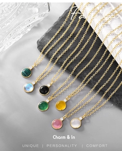 Close-up of assorted round gemstone pendants on gold-plated chains in various vibrant colors
