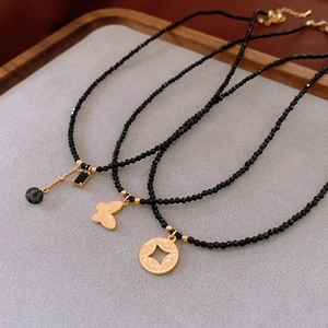 Detailed flat lay of three layered black bead necklaces with gold butterfly and drop pendants
