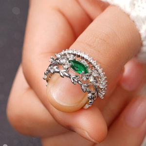 Vista macro de set de anillos de plata con piedra marquesa verde y diseño de hoja
