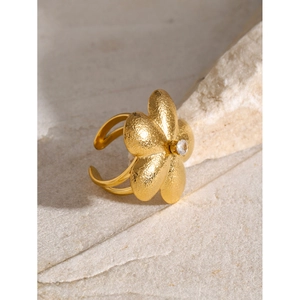 Macro view of matte 18k gold flower ring with rhinestone center on textured stone