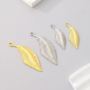 Detailed view of hollow leaf pendants in gold and silver stainless steel finishes