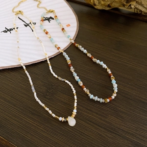 Flat lay of ethnic beaded necklaces with natural stones and water drop pendant on wood