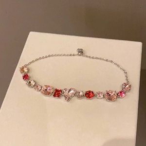 Close-up of heart-shaped pink and red zircon stones on a silver-tone link bracelet