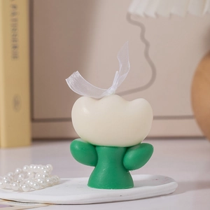 Close-up of a white tulip scented candle with green stem and elegant white silk ribbon