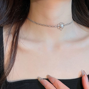 Close-up of a silver floral pendant necklace with a pearl center on a model's neck
