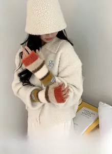 Gros plan sur les mitaines tricotées arc-en-ciel et le bob en peluche blanc cassé