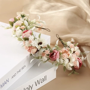 Dettaglio di una corona floreale da sposa con rose rosa e margherite su vecchi libri