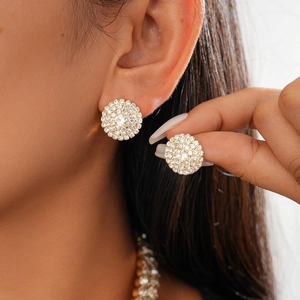 Close-up of sparkling gold geometric earrings with pavé diamond crystals on model