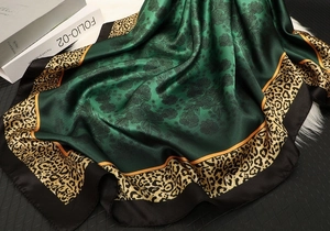 Close-up of vintage green silk scarf with floral and leopard prints on plush background