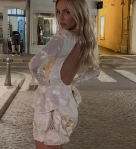 Detail view of a white lace embroidered backless dress with a large side floral accent