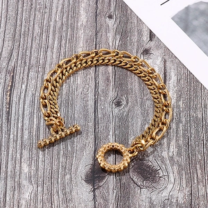 Detail of gold double-layer chain bracelet with Cuban links and ornate toggle clasp