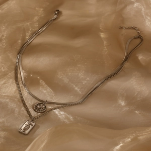 Detail of silver double-layered star and moon pendant necklace on a satin background
