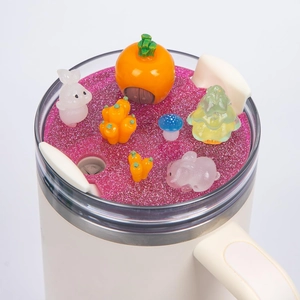 Detail of 40oz tumbler lid with pink glitter, resin rabbits, and mushroom decorations