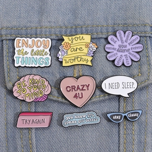 Detailansicht von neun bunten Emaille-Motivations-Pins auf blauem Jeansstoff