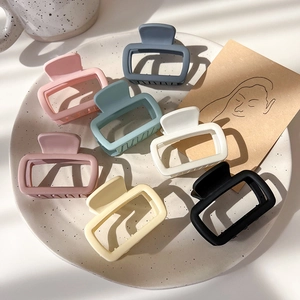 Set of 7 matte square hair claws in cream and pastel colors on a white ceramic plate