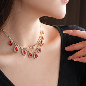 Close-up of gold necklace with ruby teardrop pendant and rhinestones on model