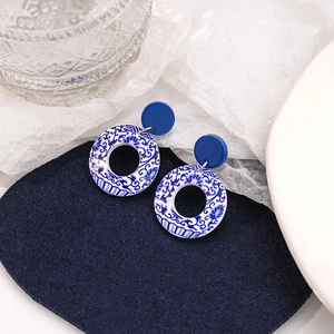 Detail of blue and white porcelain pattern acrylic hoop earrings on navy velvet