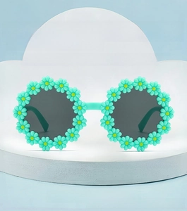 Detailed view of mint green flower sunglasses with 3D daisies on a white pedestal