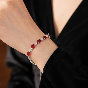Close-up of elegant silver bracelet with red oval zircons and white crystals on wrist