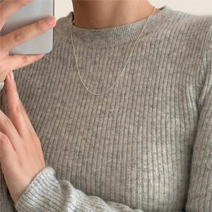 Close-up of minimalist 925 sterling silver beaded necklace worn on a grey sweater