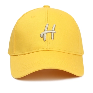 Détail d'une casquette de baseball jaune avec broderie 3D de la lettre H en argent
