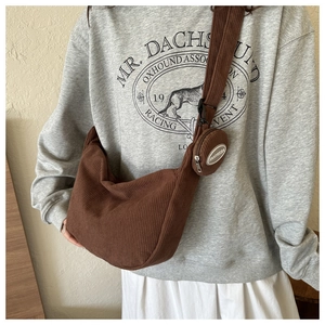 Detail of a brown corduroy crossbody bag with matching small coin purse on a model