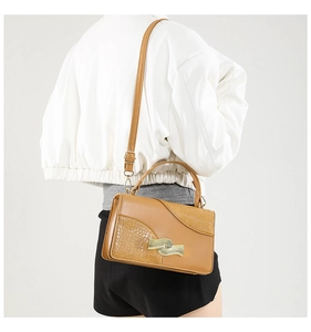 Detail of vintage camel shoulder bag featuring crocodile texture and gold wavy lock buckle