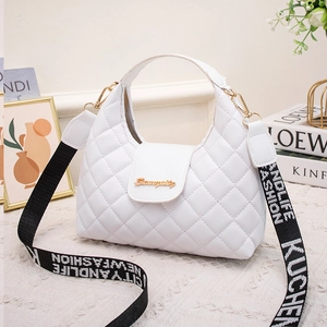White quilted handbag with gold hardware and wide lettered shoulder strap in a lifestyle setting