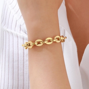 Detailed view of a gold chunky chain link bracelet worn on a wrist with textured fabric