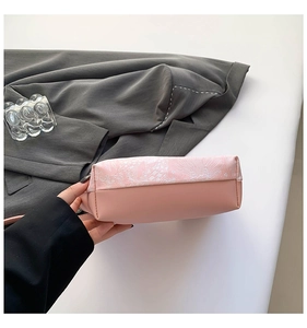 Detailed view of pink handbag featuring floral embroidery and textured stitching base
