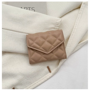 Close-up of beige quilted leather mini wallet with stylish diamond pattern and clasp