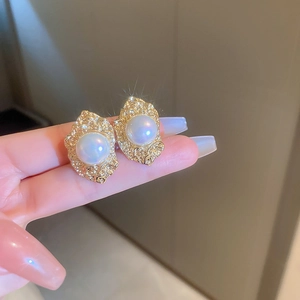 Detailed view of vintage gold flower pearl earrings held by hand showing fine texture