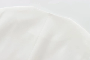 Detail of white woven fabric texture and structured shoulder seam on minimalist jacket