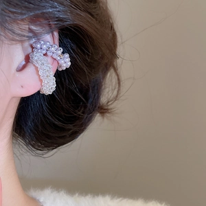 Close-up of elegant beaded ear cuffs in clear and lavender colors worn by a model
