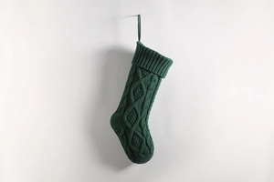 Close-up of a dark green knitted Christmas stocking with classic cable stitch patterns