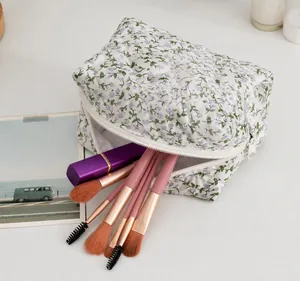 Detail view of a floral quilted cosmetic bag showing its large storage capacity with brushes.