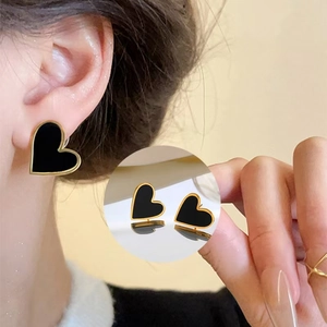 Detail shot of heart-shaped black and gold earrings on model showing fine craftsmanship