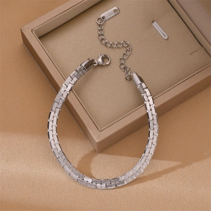 Polished silver Cuban link steel bracelet on satin fabric background with gift box