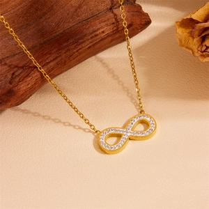 Détail du collier infini doré avec petits cristaux blancs sur fond texturé beige